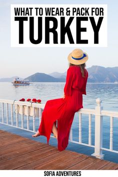 a woman in a red dress and hat sitting on a pier with the words what to wear & pack for turkey