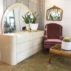 a living room filled with furniture next to a mirror and potted plant on top of a table