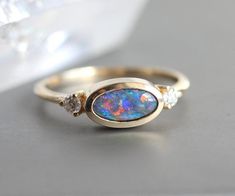 an opal and diamond ring sitting on top of a table