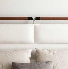 a white bed with two wooden head boards above it and pillows on the bottom side