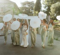 the bridesmaids are walking down the street with their white parasols over their heads