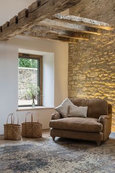 a living room with a couch, chair and two baskets in front of a window