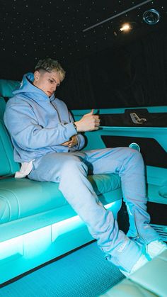 a man sitting on top of a blue couch in a room filled with white lights