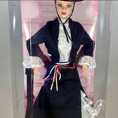 a doll in a glass case wearing a black dress and hat