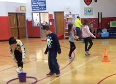 several children are playing with hula hoops in the gym