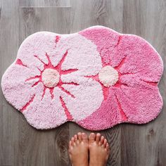 someone is standing on the floor with their feet propped up next to a pink flower rug