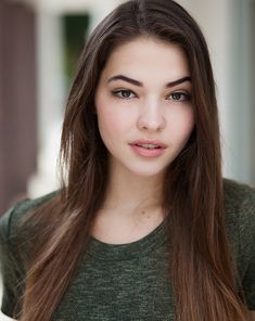 a woman with long brown hair is posing for the camera while wearing a green shirt