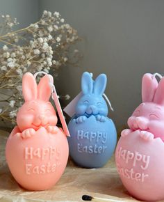 three plastic easter eggs with bunny ears on them and happy easter written in white letters