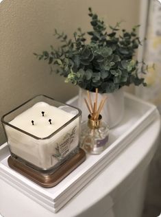 a candle sitting on top of a white table next to a potted plant