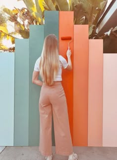 a woman standing in front of a colorful wall with her back to the camera and holding onto an orange handle