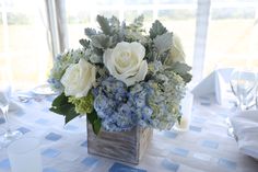 a vase filled with white and blue flowers on top of a table