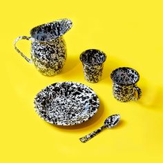 three cups and two spoons on a yellow background with speckled paint, one has a silver handle