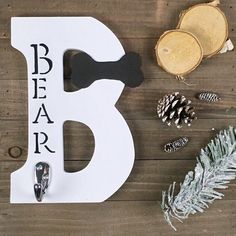 a wooden sign with the letter b on it next to pine cones and other decorations