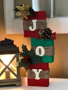 a christmas decoration made out of wood blocks with the word joy painted on it and pine cones