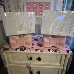 two pink hello kitty mugs sitting on top of a white dresser next to each other