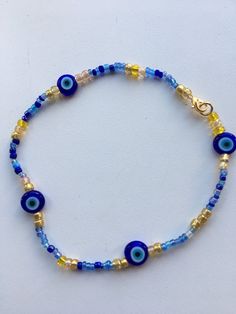 Evil eye protection bracelet with flat evil eye protection glass beads and gold and blue mix seed beads. Finished with gold tone lobster clasp. Choose your length Blue Heishi Beads Bracelet With Gold Accents, Blue Heishi Beads Bracelet With Gold Beads, Festival Beaded Evil Eye Bracelet, Adjustable Blue Evil Eye Bracelet With Colorful Beads, Handmade Blue Evil Eye Bracelet With Round Beads, Blue Evil Eye Bracelet For Festivals, Blue Beaded Bracelets With Gold Beads For Beach, Blue Jewelry With Lobster Clasp For Festival, Blue Evil Eye Bracelet With Spacer Beads