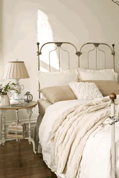 a bedroom with white walls and wooden flooring is pictured in this image, there are two lamps on the nightstands next to the bed