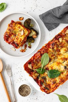 two white plates topped with lasagna casserole next to broccoli