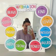 a woman taking a selfie in front of a mirror with different words on it