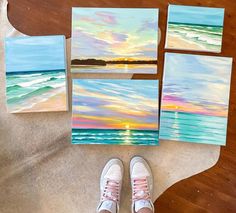 a person standing next to some paintings on the floor with their feet propped up in front of them