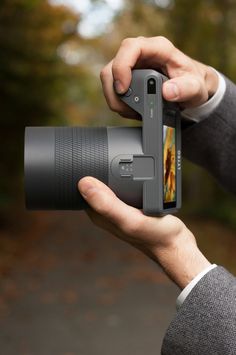 a person holding a camera in their hand and taking a photo with the lens up