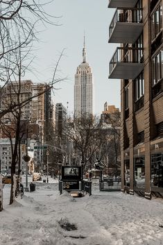 the city is covered in snow and has tall buildings on both sides, with no cars or people