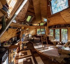 a living room filled with furniture and lots of windows in the roof top area, surrounded by wood paneling