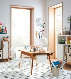 a room with a desk, chair and bookshelf filled with art supplies in it