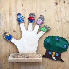 three finger puppets are placed next to a wooden block with a tree and house on it