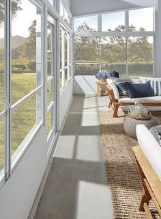 the sun shines in through large windows on an empty room with couches and chairs