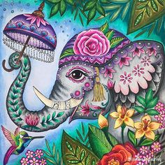 an elephant with flowers on it's head holding an umbrella