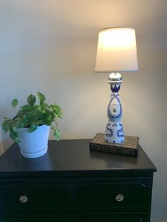 a blue and white vase sitting on top of a black dresser next to a lamp