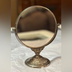 a mirror sitting on top of a table next to a white cloth covered bedding