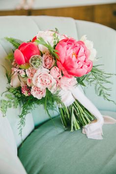 a bridal bouquet sitting on top of a green chair in front of a window