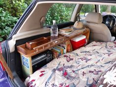 a bed in the back of a car next to a table with books on it