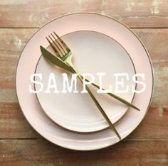 a white plate topped with two forks next to a pink and white plate on top of a wooden table