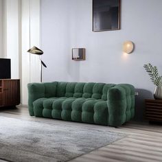 a living room with a green couch and television on the wall in front of it