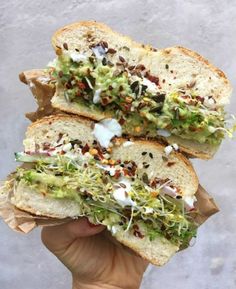 two pieces of bread with various toppings on it in someone's hand,