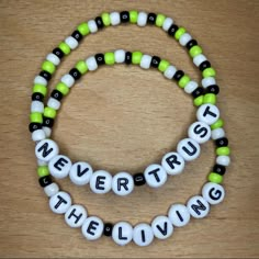 two bracelets that say never trust the living and one with green, white and black beads