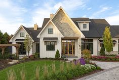 a white house with lots of windows and landscaping around it's front lawn area