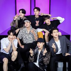 the group of young men are posing together for a photo in front of purple walls