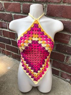 a white mannequin wearing a pink and yellow crocheted halter top