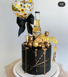 a black and gold birthday cake decorated with confetti, chocolates, and balloons