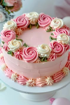 a cake with pink frosting and white flowers on the top is sitting on a table