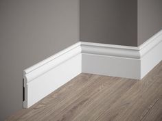 the corner of an empty room with wood flooring and white mold moulder