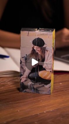 a person sitting at a table with a laptop and a box on it that has an image of a woman