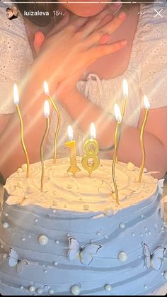 a woman holding a baby in front of a cake with lit candles on it,