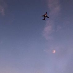 an airplane is flying in the sky at sunset or dawn with half moon visible behind it