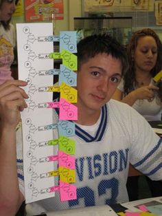 a young man holding up a large stack of sticky notes with numbers on each side