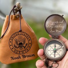 a hand holding a compass and a leather pouch with the words united states army on it